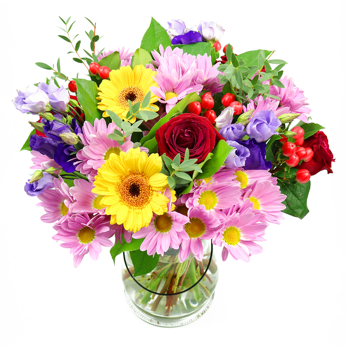 A vibrant mixed bouquet is captured in a clear glass vase, placed before a white background that allows each flower to stand out as if suspended in air. At the heart of the arrangement, sumptuous dark red roses create a rich focal point, their velvety petals tightly layered and glowing with a romantic intensity. Nestled nearby, two bright yellow gerbera daisies with deep brown-orange centres add a sunny, welcoming expression, like smiling faces within the design. Flowing outward, generous clusters of pink chrysanthemums and daisies soften the palette, their many delicate petals opening wide around tiny yellow centres, contributing both volume and a comforting, familiar charm. Among these, purple and lavender lisianthus blooms rise gracefully, their bell-shaped, slightly curled petals introducing a cool, elegant counterpoint and a sense of gentle movement. Dotted through the foliage, small, round red hypericum berries glisten, adding both structure and a slightly festive touch. The whole arrangement is wrapped in layers of green foliage, from broad, darker leaves that anchor the bouquet to finer, paler sprigs that lift and lighten the overall look, reminiscent of the leafy avenues around Emerson Park. Through the glass vase, the criss-cross of neatly cut stems can be seen resting in clear water, a quiet reminder of the bouquet's freshness and careful preparation. The lighting appears soft and even, making this arrangement feel like it is ready to be placed on a dining table in a home just off Wingletye Lane, perfect for marking birthdays, anniversaries, or simply brightening an everyday afternoon with colour and fragrance.
